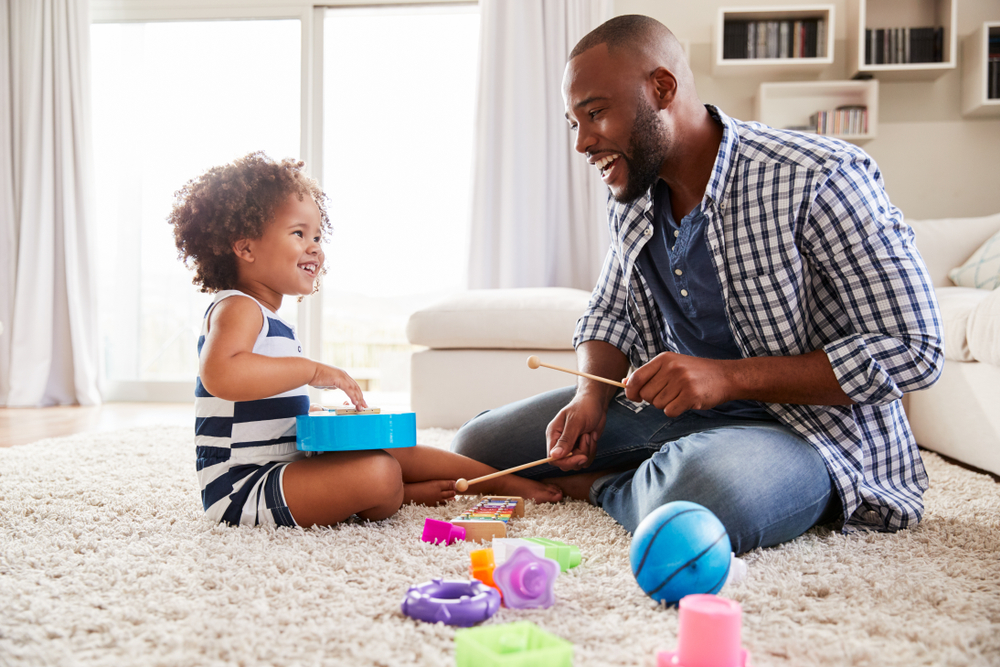 Man and toddler playing on the floor with toys