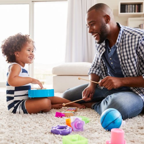 Man and toddler playing on the floor with toys